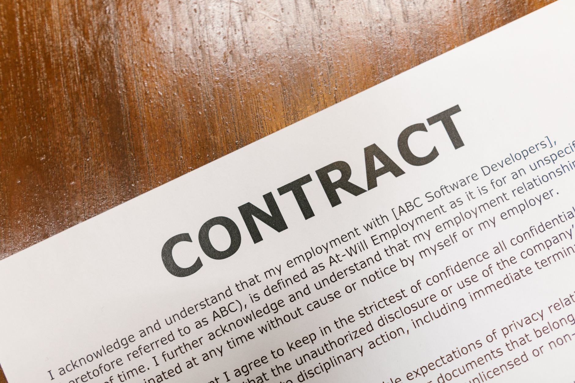 nulurencontract afschaffing 2028 — A detailed close-up of a printed contract document on a wooden table surface.