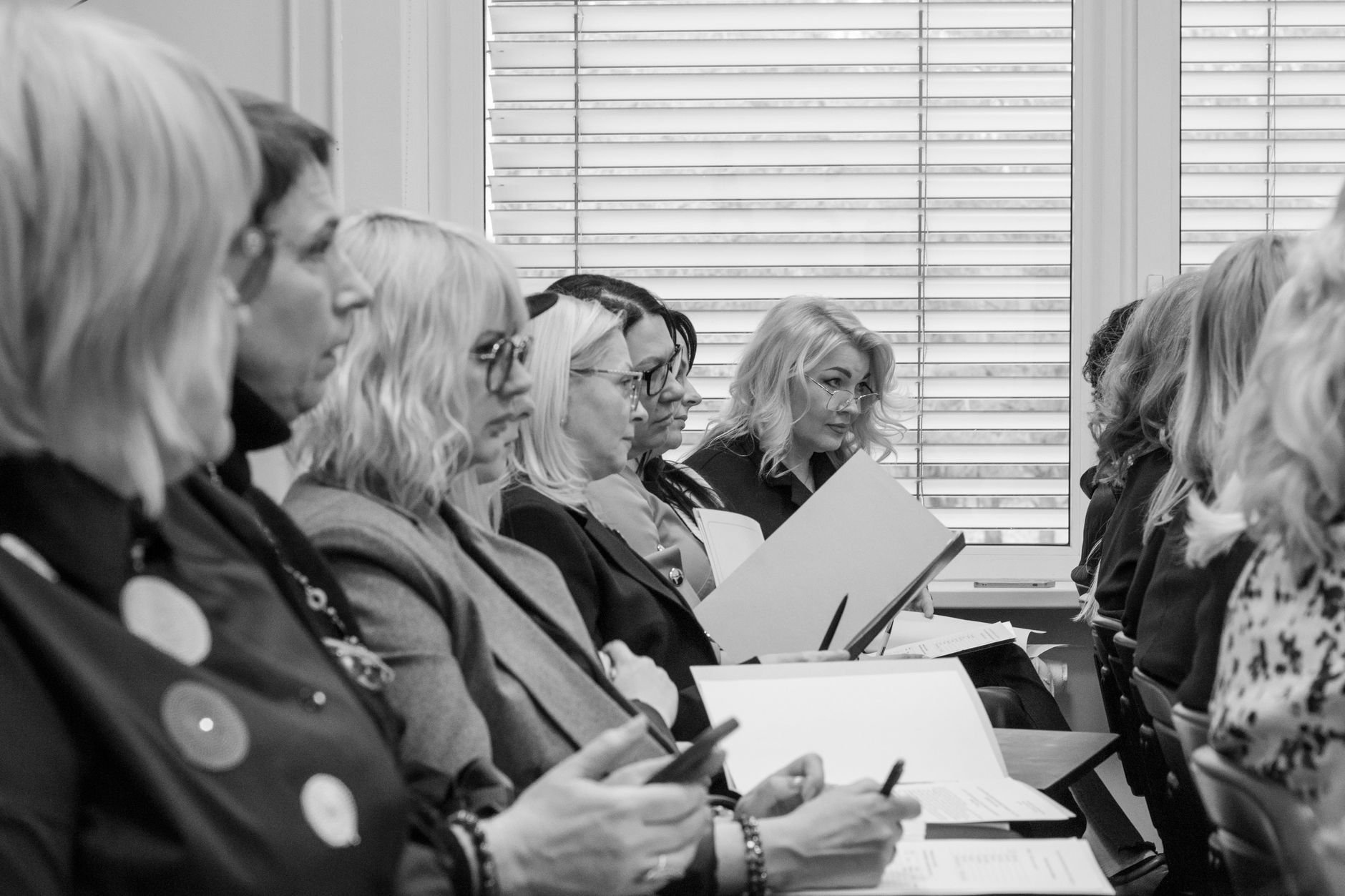 personeelsbeleid — Black and white image of women in a meeting, attentively taking notes.