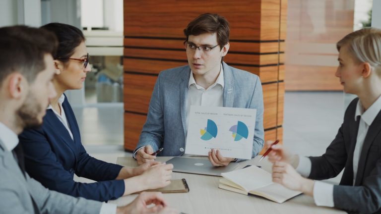 performance management cyclus — Man presenting charts to colleagues in a meeting.