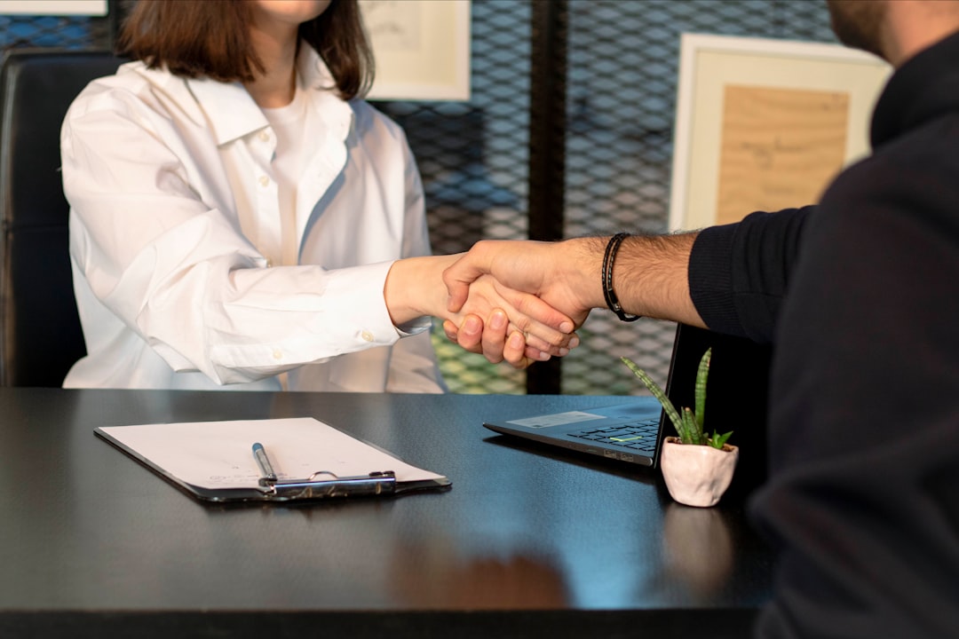 salarisonderhandeling jonge werknemers — a man and a woman shaking hands in front of a laptop